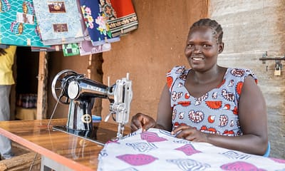 Alice Ledu in Bidi Bidi Settlement attending to the tailoring enterprise that she started using proceeds from her catering business skills. Photo: UN Women/Jeroen van Loon